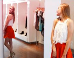 Kuva tytöstä seisomassa peilin edessä, kokeilemassa vaatteita. 