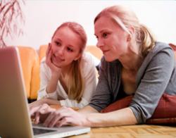 Kuva äidistä ja tyttärestä käyttämässä tietokonetta yhdessä. Kuva kuvastaa kommunikoinnin tärkeyttä ja tyttären auttamista oikean tiedon löytämisessä. 